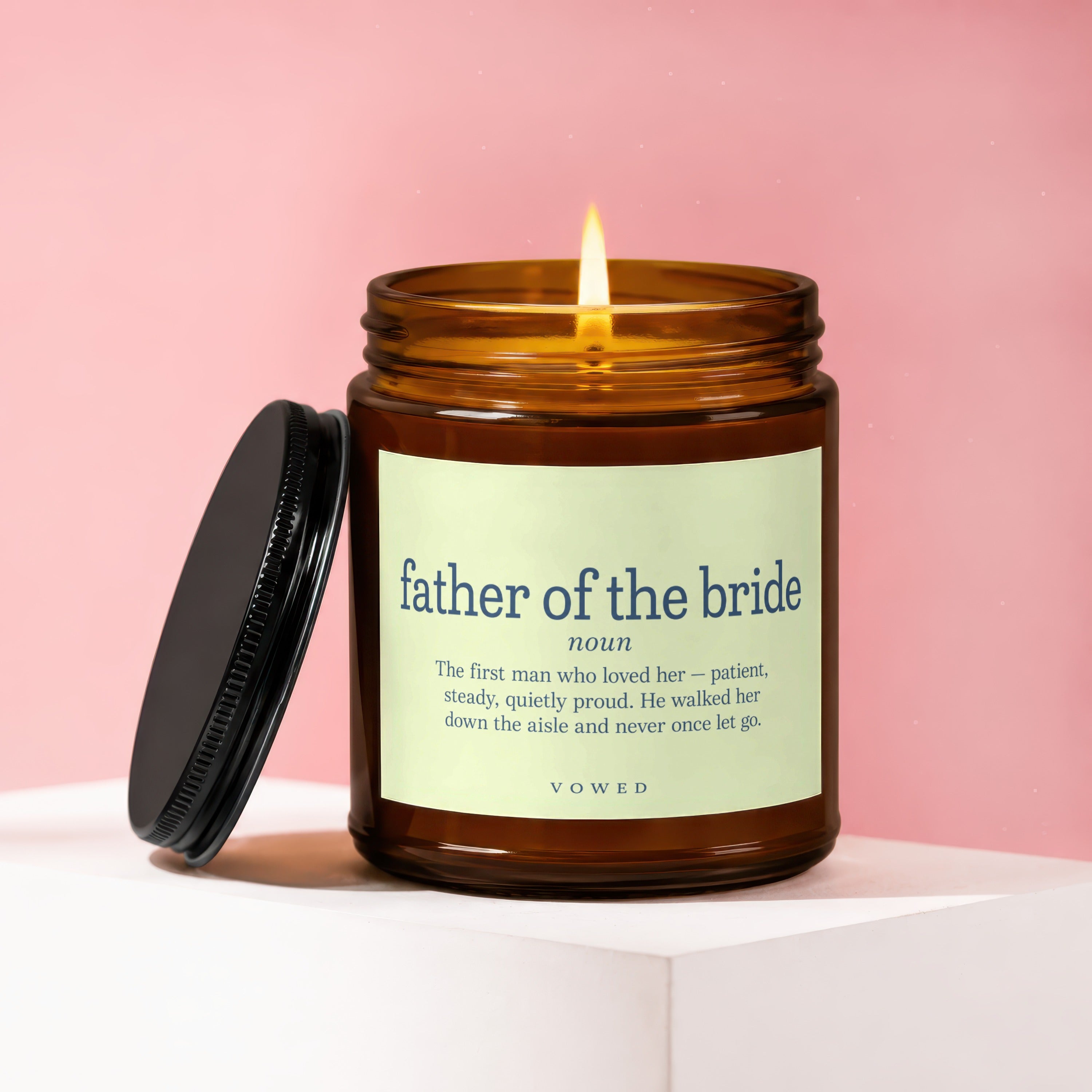 Lit amber candle with "father of the bride" definition on label.
