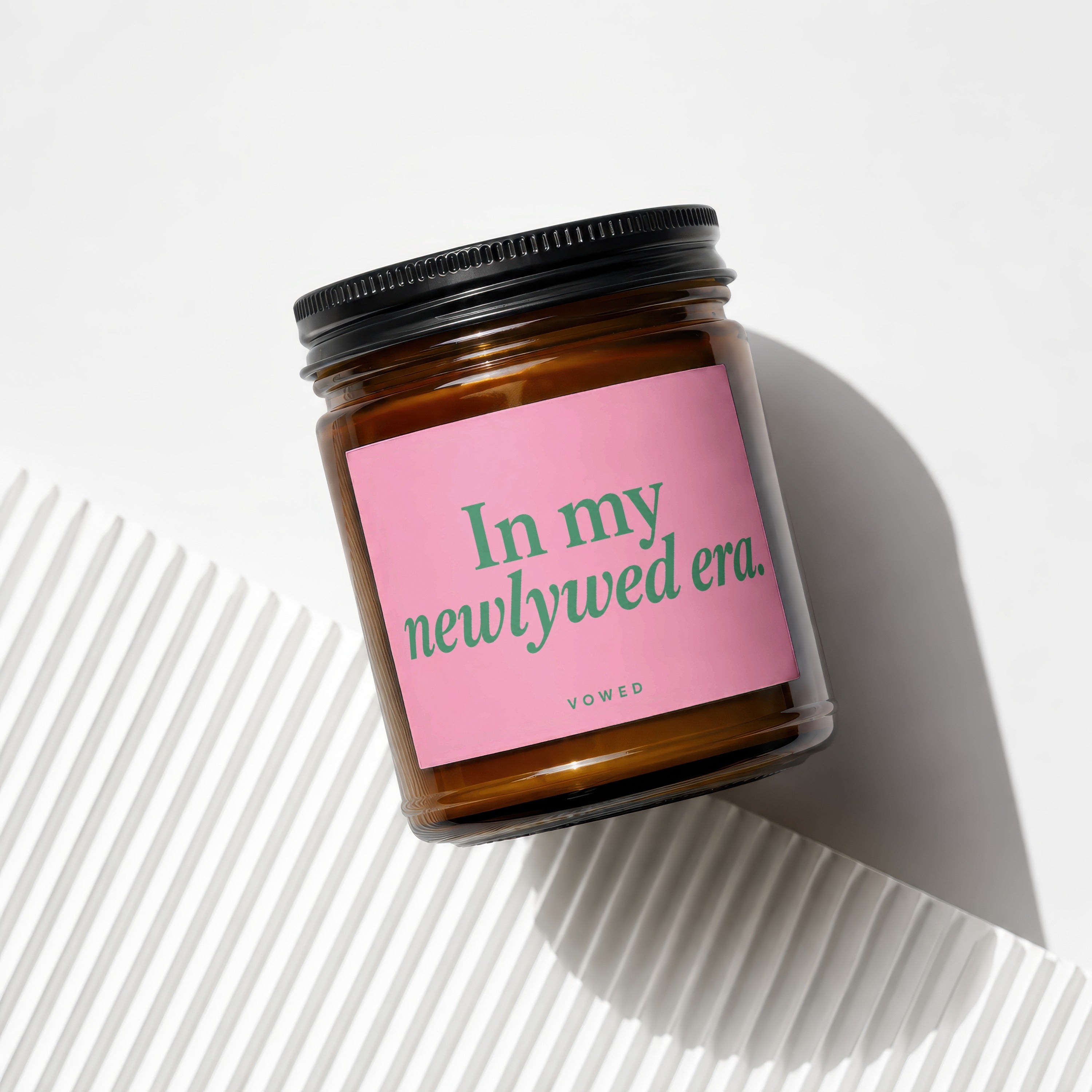 Amber jar candle with pink label reading "In my newlywed era. vowed."