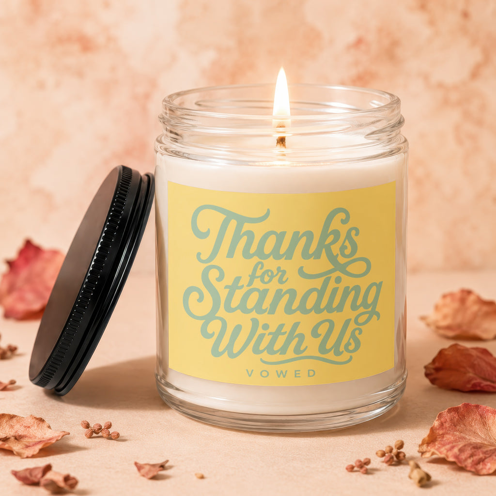 Jar candle with lit wick, yellow label reads "Thanks for Standing With Us".
