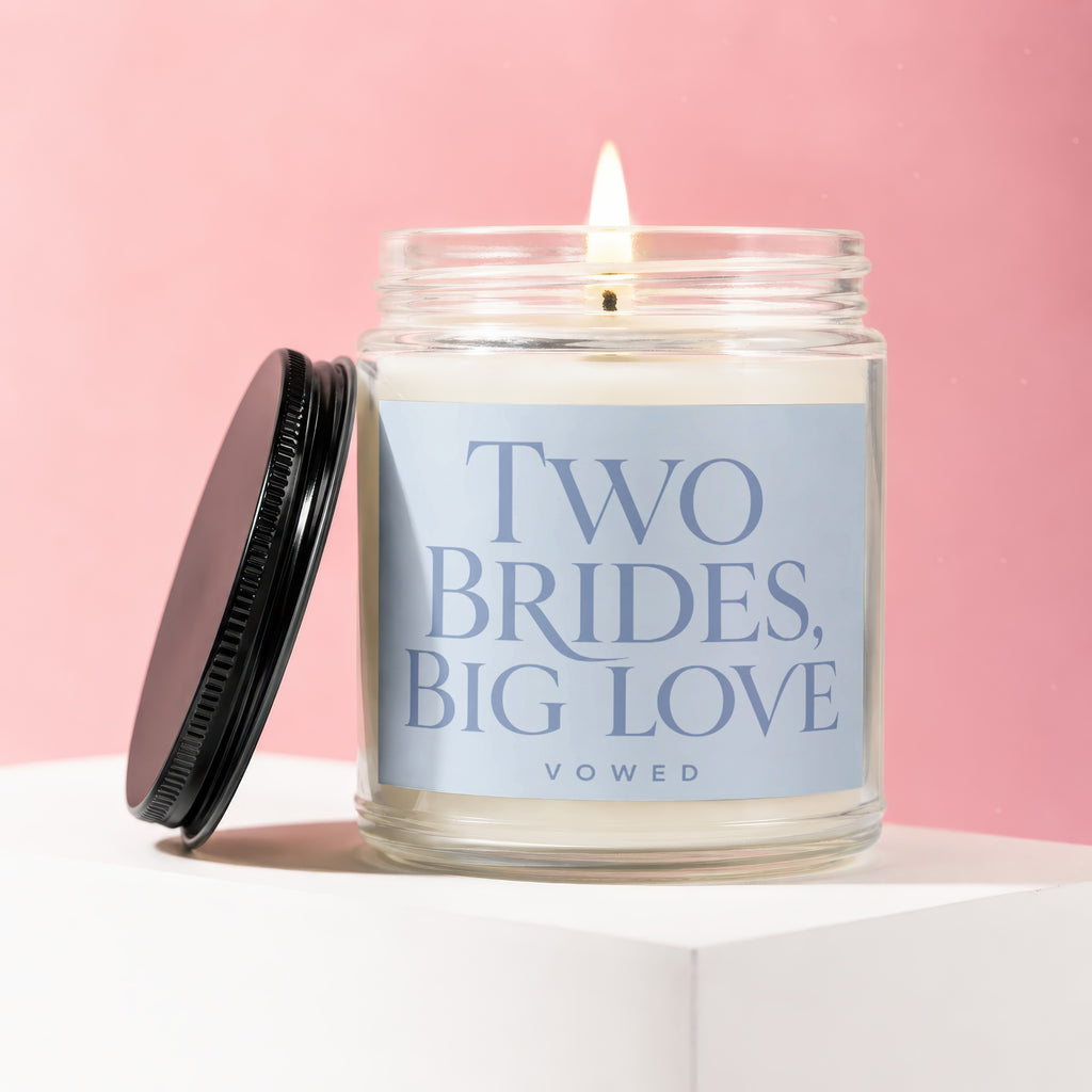 Lit candle in jar with black lid off, label reads "TWO BRIDES, BIG LOVE".