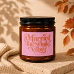 Amber jar candle with pink label reading "Married the whole Vibe VOWED".