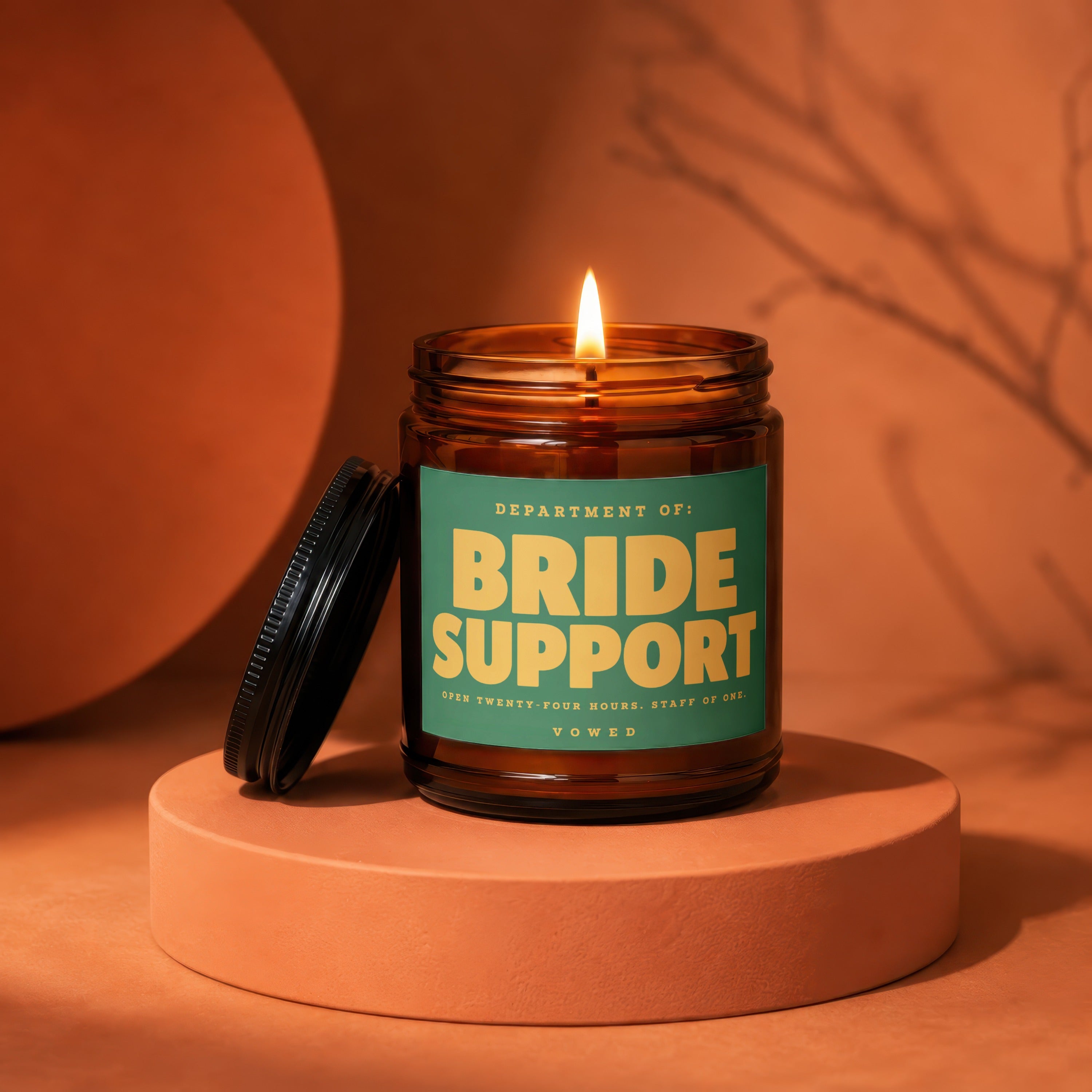 Amber jar candle with lid off, lit flame, reads "Bride Support".