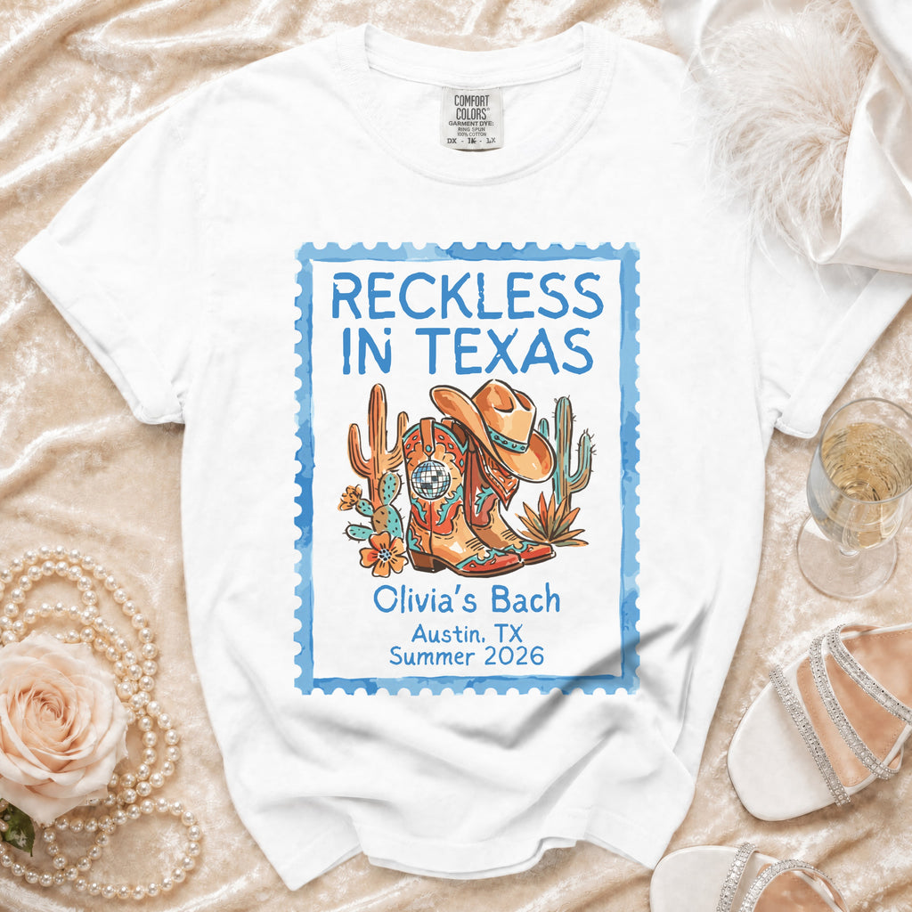 White t-shirt with "Reckless in Texas" stamp, cowboy boots, cactus, and hat.