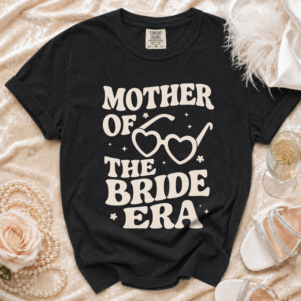 Black t-shirt with "Mother of the Bride Era" text and heart-shaped glasses graphic.