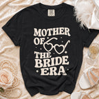 Black t-shirt with "Mother of the Bride Era" text and heart-shaped glasses graphic.