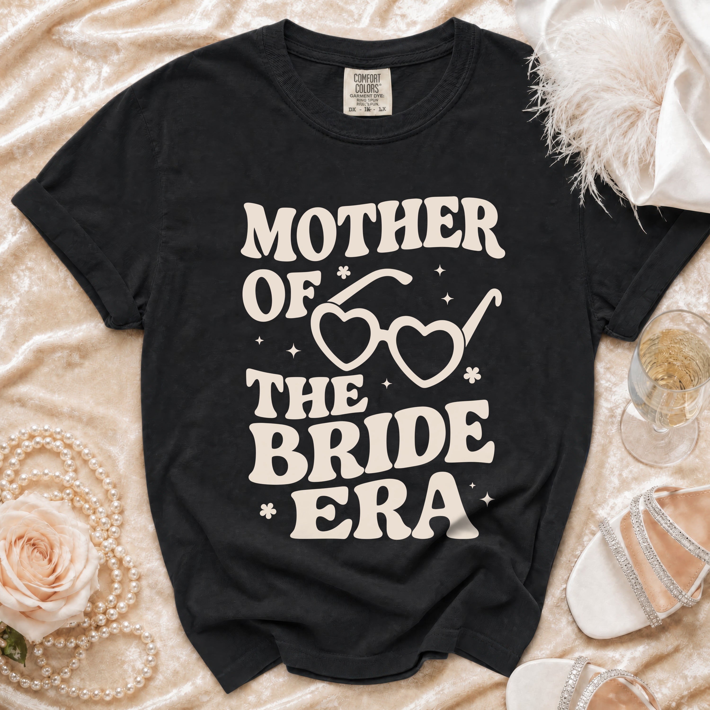 Black t-shirt with "Mother of the Bride Era" text and heart-shaped glasses graphic.