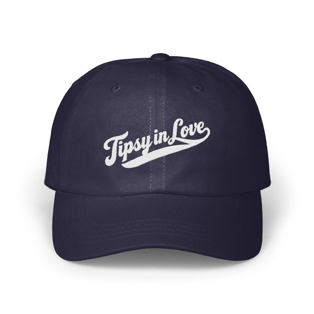 A dark navy blue baseball cap with embroidered white text reading Tipsy in Love on the front.