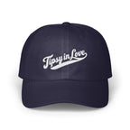 A dark navy blue baseball cap with embroidered white text reading Tipsy in Love on the front.