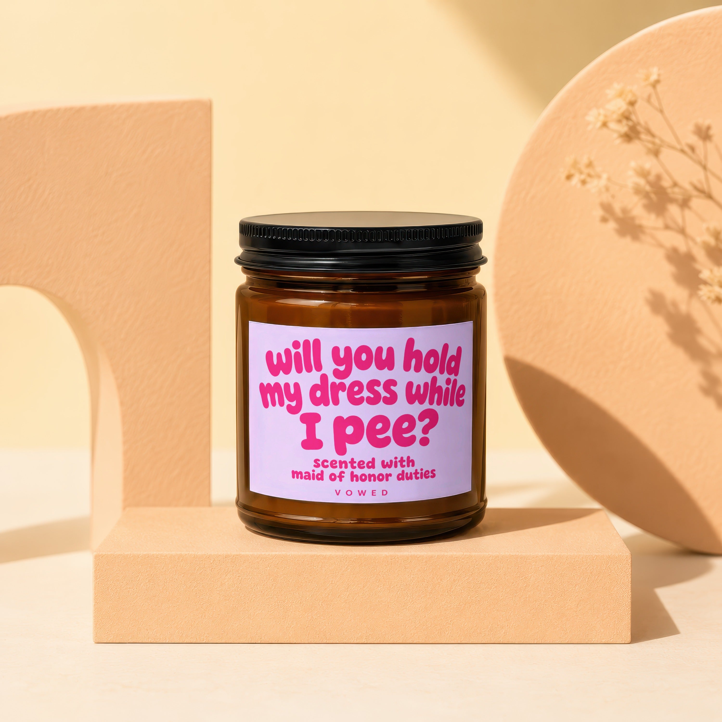 Amber jar candle with lilac label reading "will you hold my dress while I pee?"
