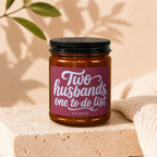 Candle with black lid, maroon label reading "Two husbands, one to-do list" and "VOWED".