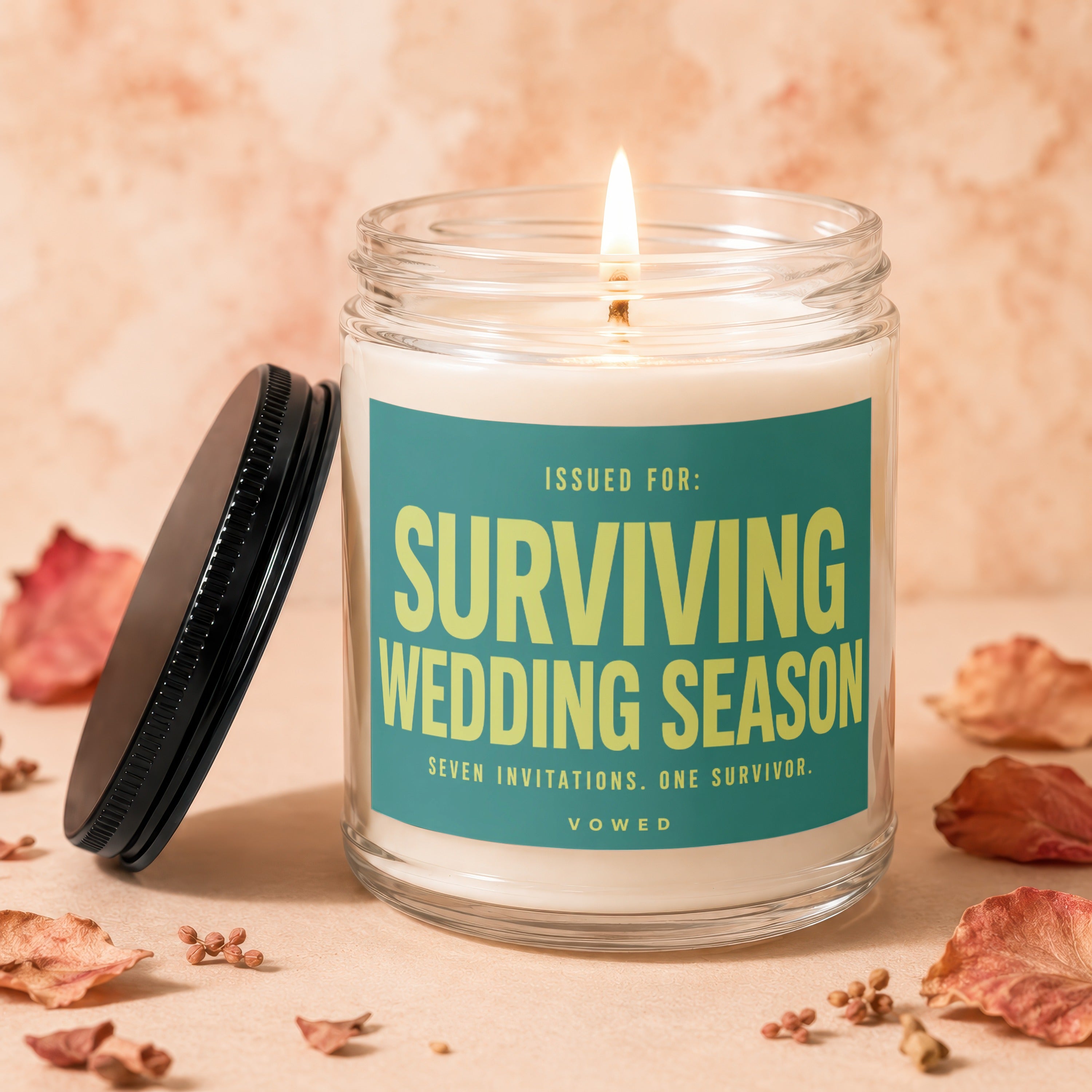 Burning candle in glass jar with teal label that reads "Surviving Wedding Season".