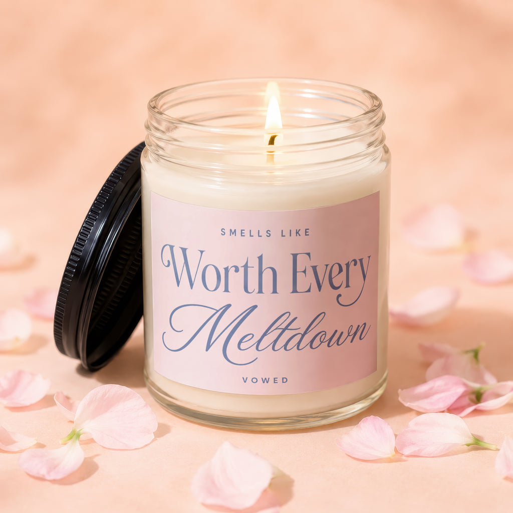 Lit candle in a jar with a pink label reading "Smells Like Worth Every Meltdown Vowed".