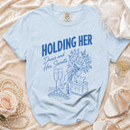 Light blue t-shirt with "HOLDING HER" and "Dress and Her Secrets" graphics.