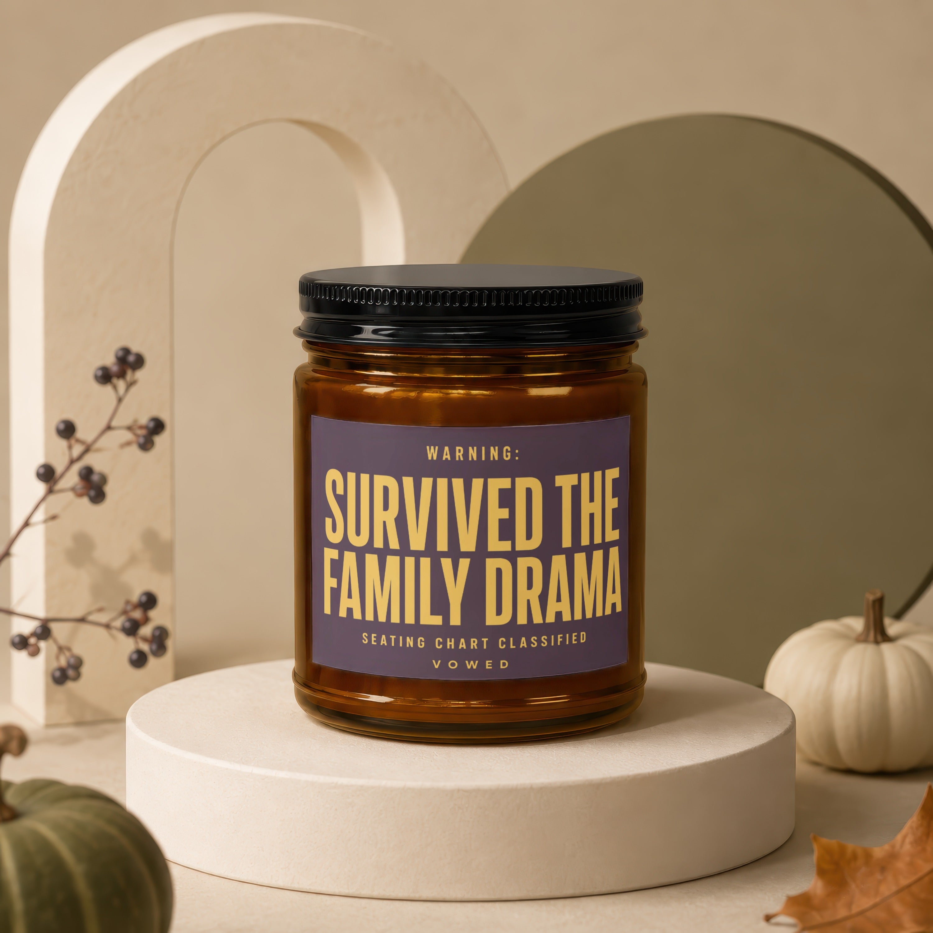 Amber jar candle with black lid labeled "Survived the Family Drama".