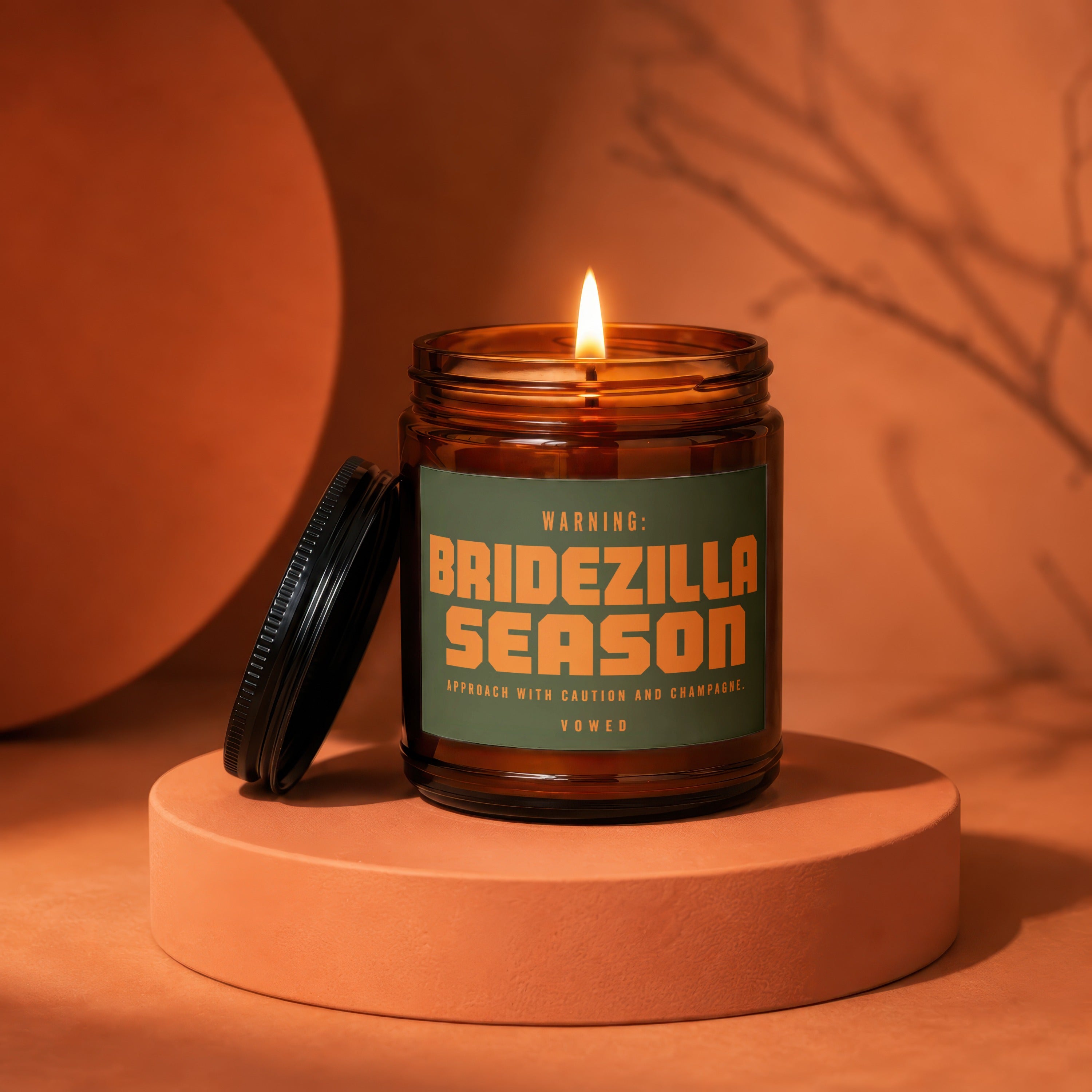 Amber jar candle with lit wick, green label reads "Bridezilla Season".