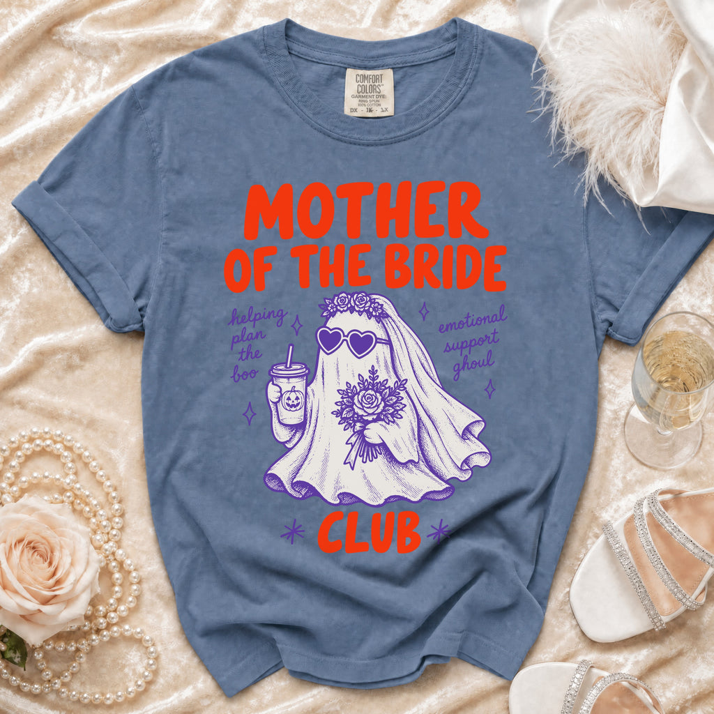 Blue t-shirt with "Mother of the Bride Club" ghost graphic, holding drink and flowers.