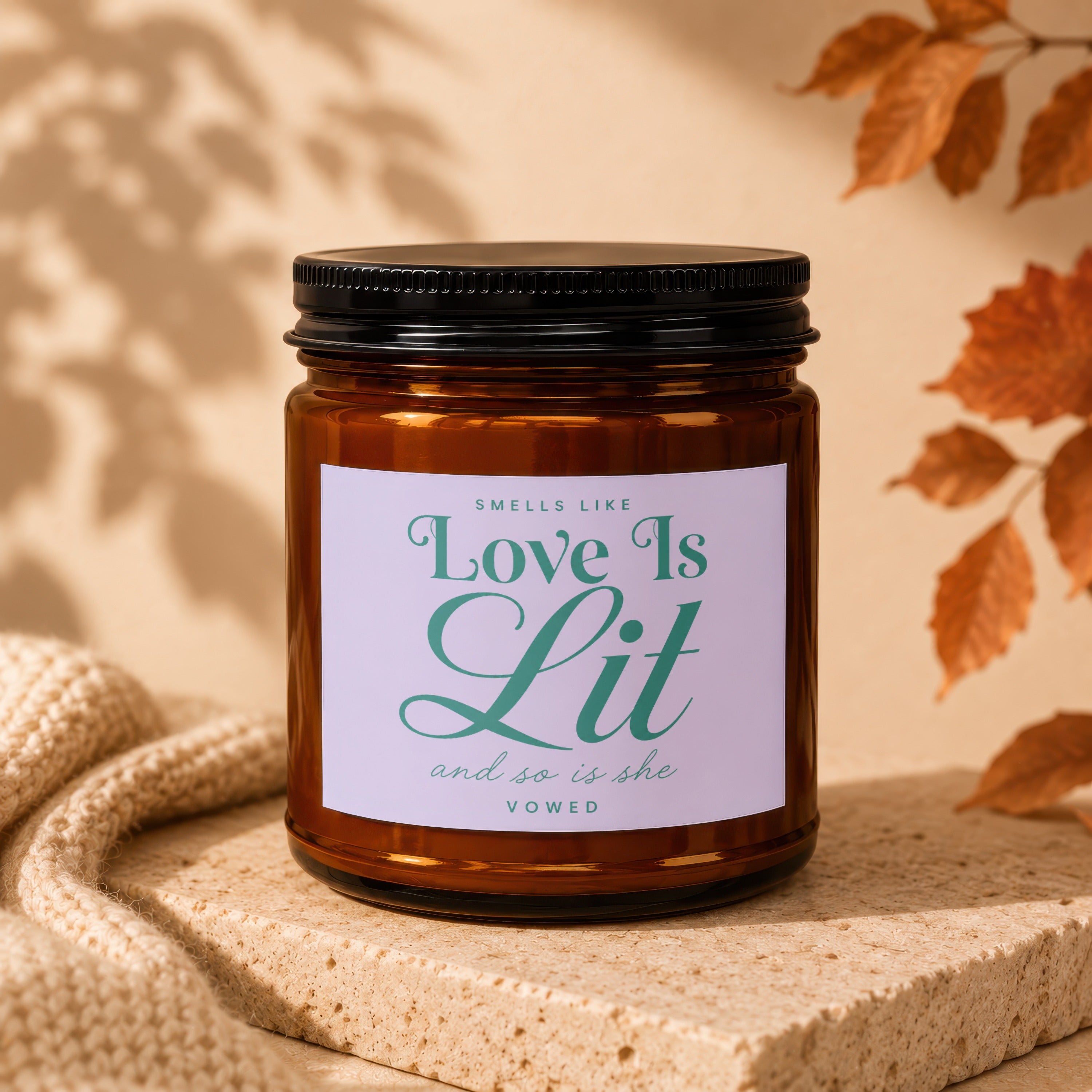 Amber candle with black lid and "Love Is Lit and so is she vowed" label.