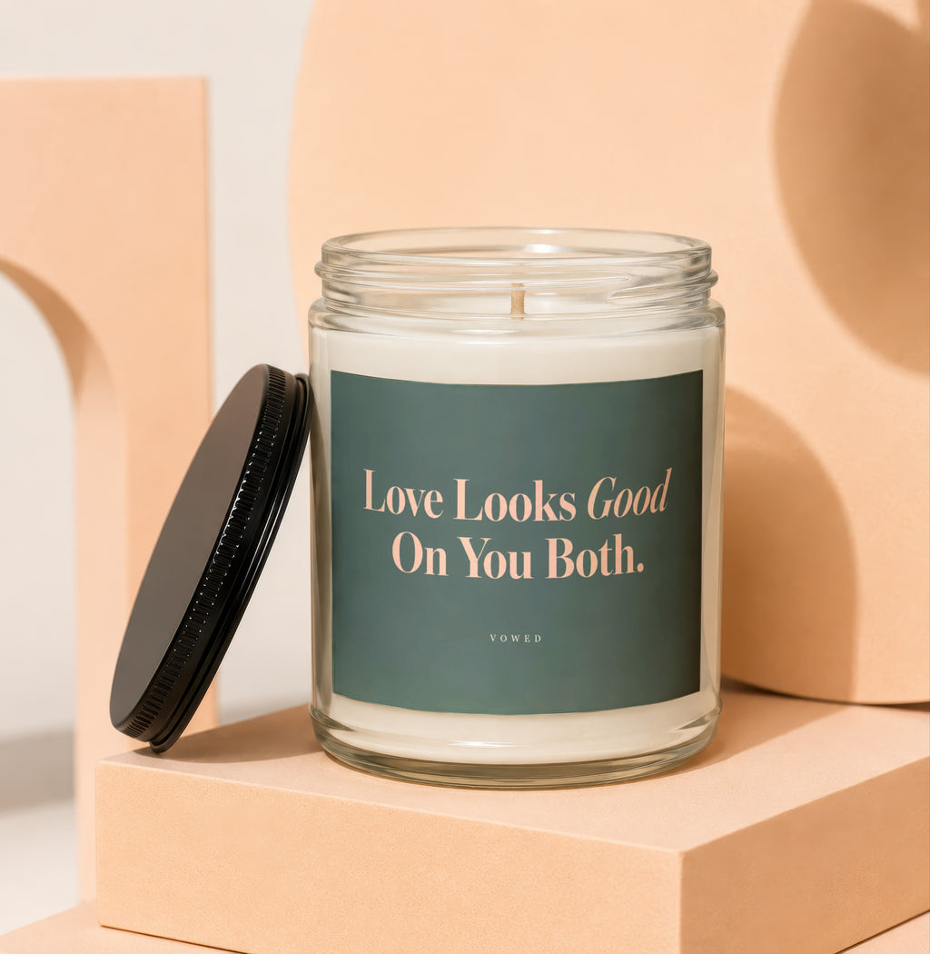 Glass candle with black lid, "Love Looks Good On You Both. VOWED" text.