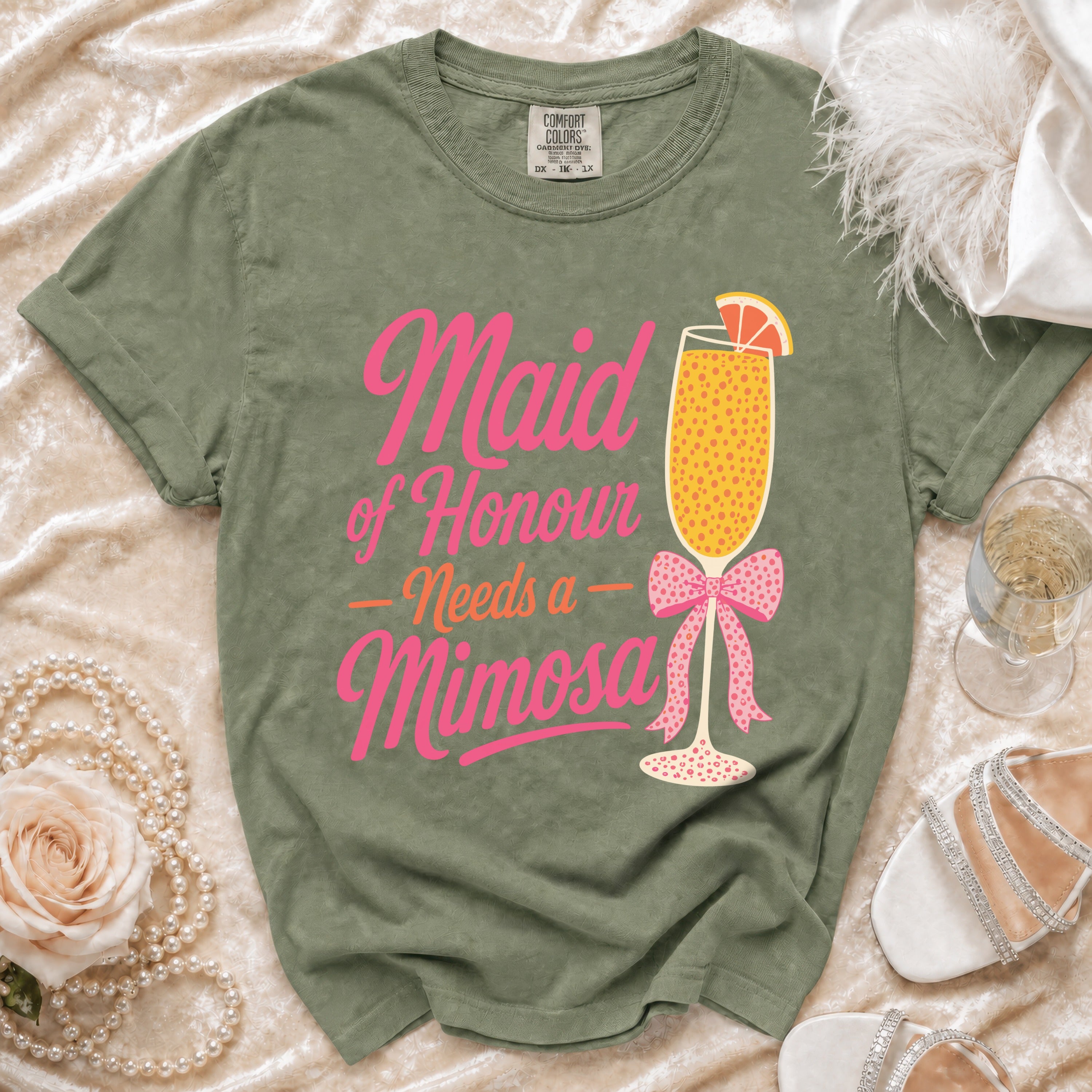 Olive t-shirt with pink text and mimosa graphic saying "Maid of Honour Needs a Mimosa".
