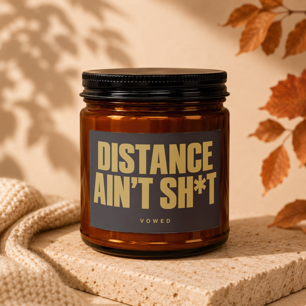 Amber glass candle with black lid and label reading "DISTANCE AIN'T SH*T VOWED".