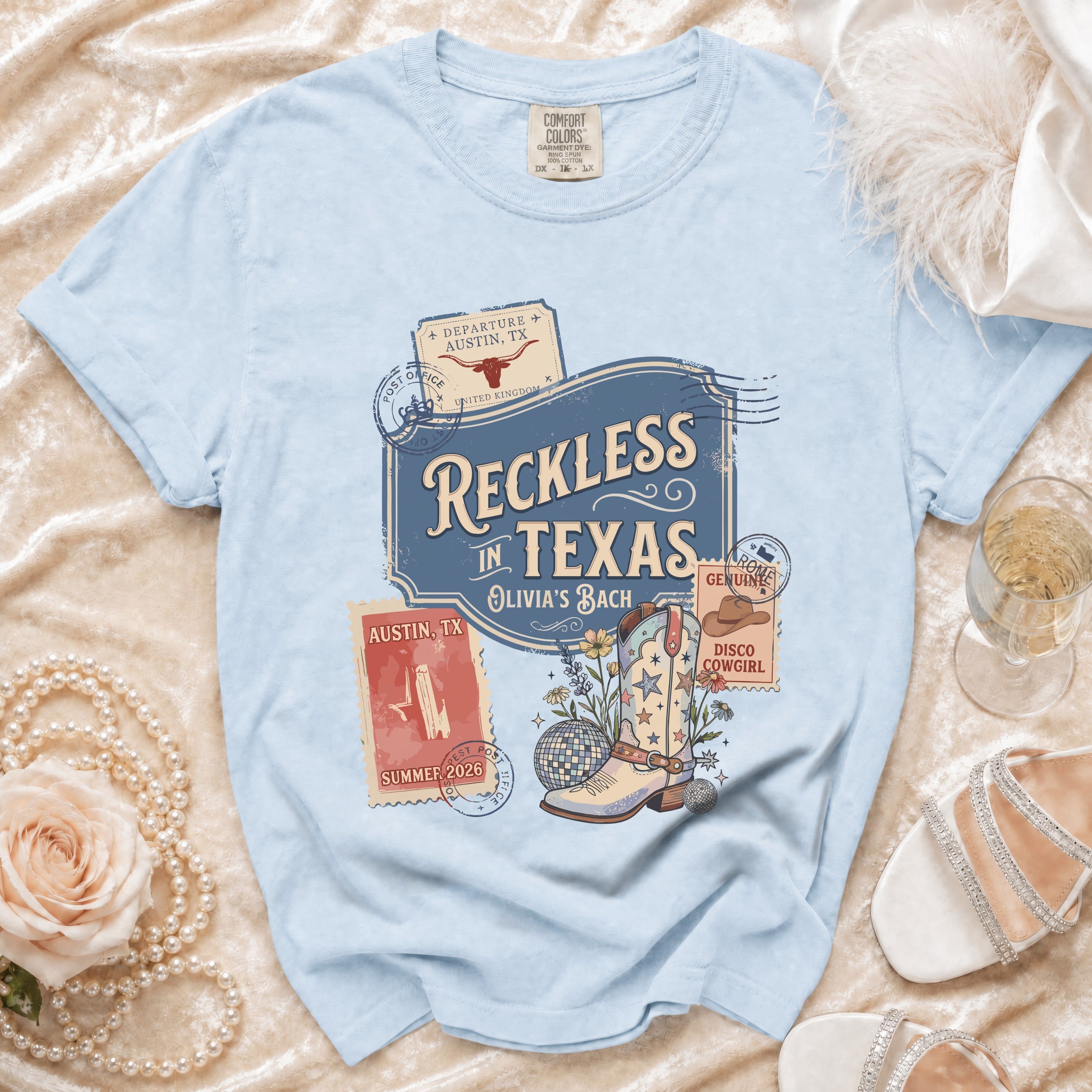 Light blue t-shirt with "Reckless in Texas" graphic and cowboy boot.