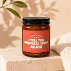 Brown glass candle with "I tell the proposal story again" text on red label.