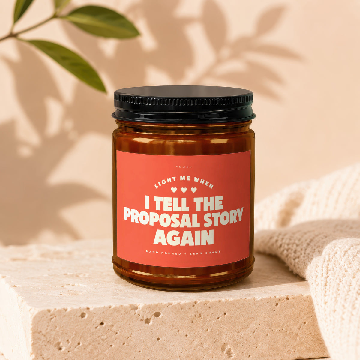 Brown glass candle with "I tell the proposal story again" text on red label.