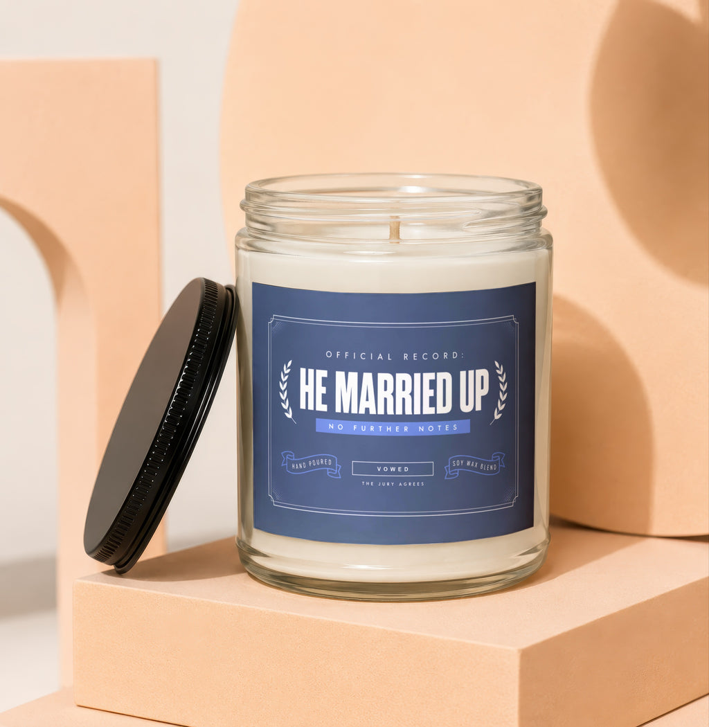 Candle with "He Married Up" label, hand poured soy wax blend.