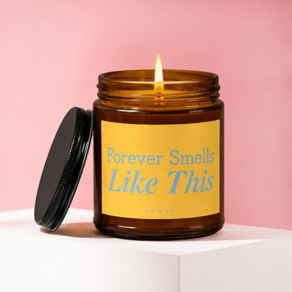 Lit candle in amber jar with yellow label reading "Forever Smells Like This".