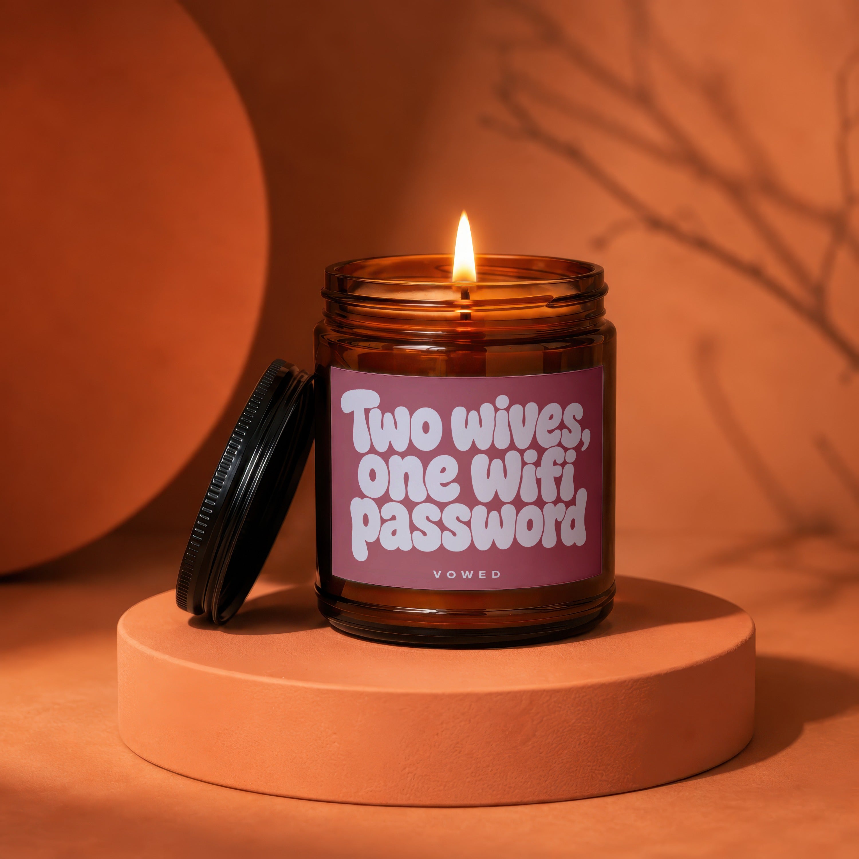 Amber jar candle with lit wick, reads "Two wives, one Wifi password".