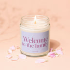 Glass jar candle with lit wick reads "Welcome to the family" and "VOWED".