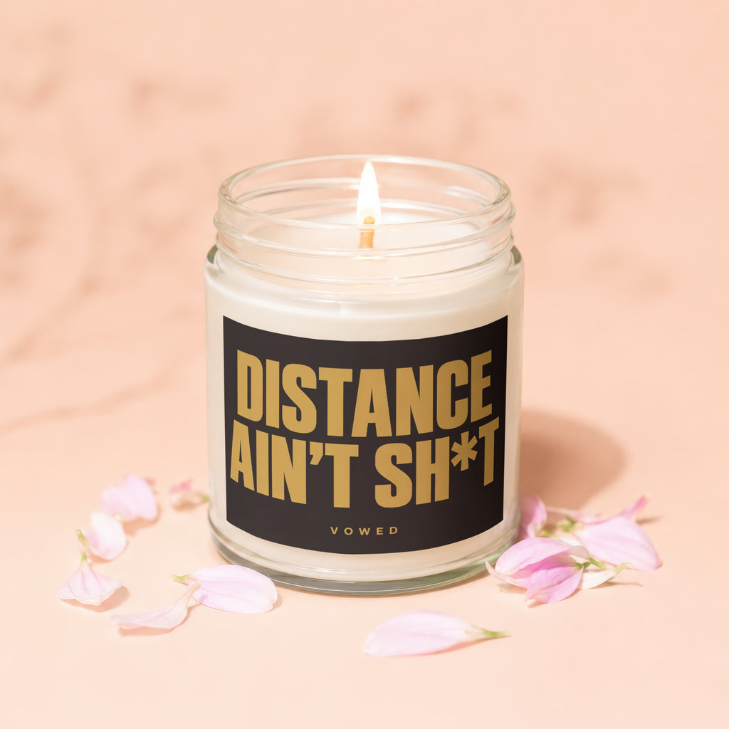 Lit candle in a glass jar with black label reading "DISTANCE AIN'T SH*T VOTED"