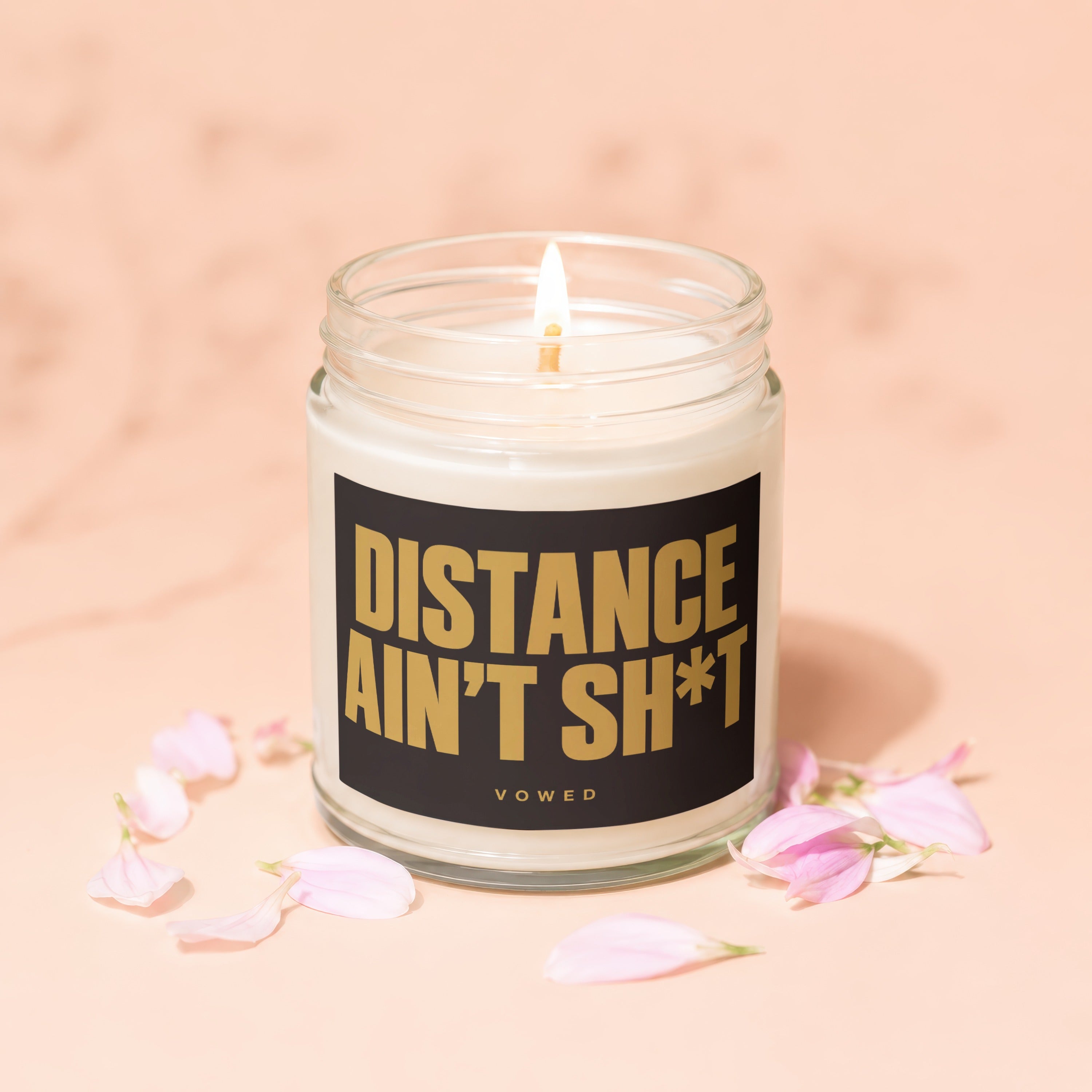 Lit candle in a glass jar with black label reading "DISTANCE AIN'T SH*T VOTED"