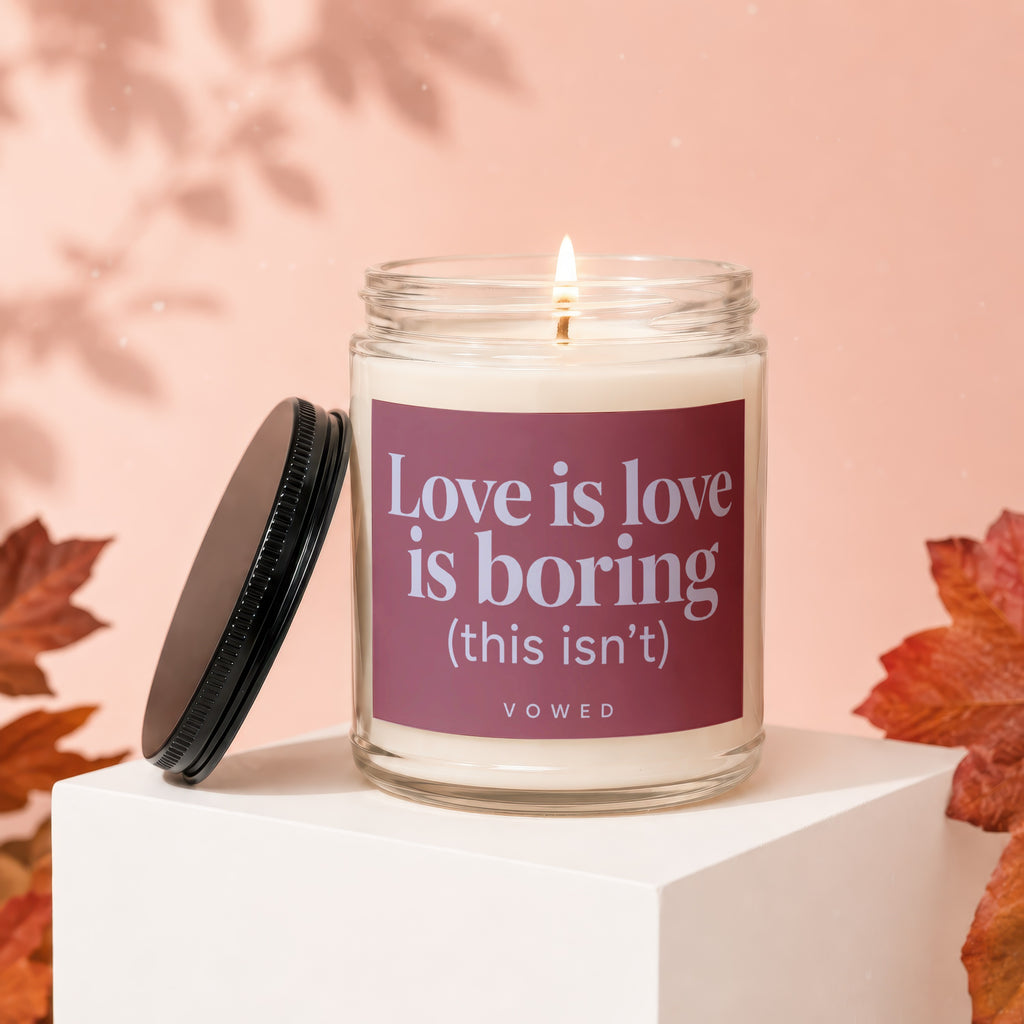 Glass candle with purple label reading "Love is love is boring (this isn't)".