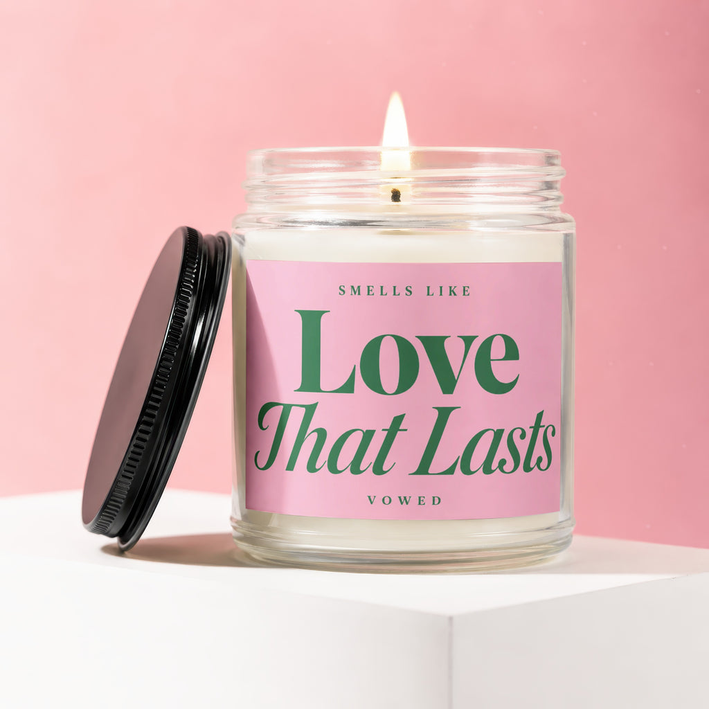 Candle in a glass jar with pink label reading "Love That Lasts" and "vowed".