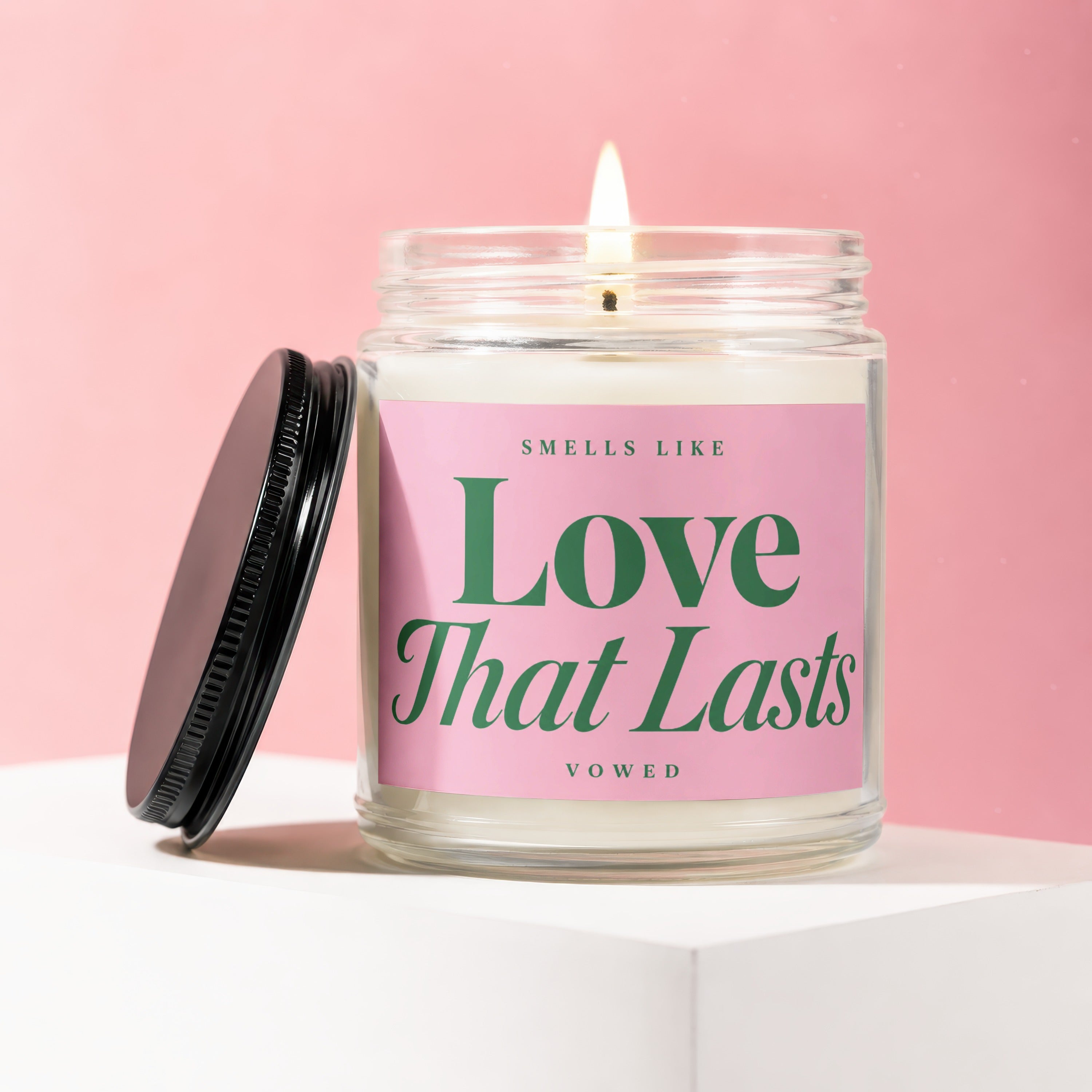 Candle in a glass jar with pink label reading "Love That Lasts" and "vowed".