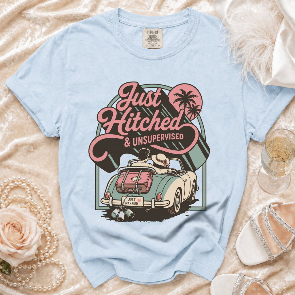 Light blue t-shirt with a graphic of a newlywed couple in a convertible with "Just Hitched & Unsupervised" text.
