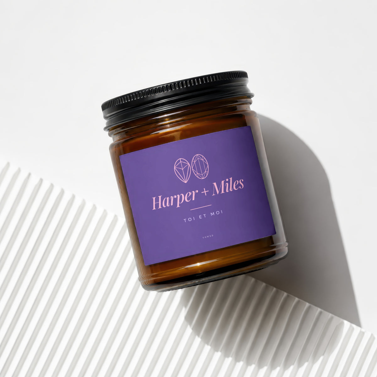 Amber glass candle with purple label reading "Harper + Miles TOI ET MOI vowed."