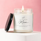 Lit candle in glass jar with "Mom" label, lid beside it.