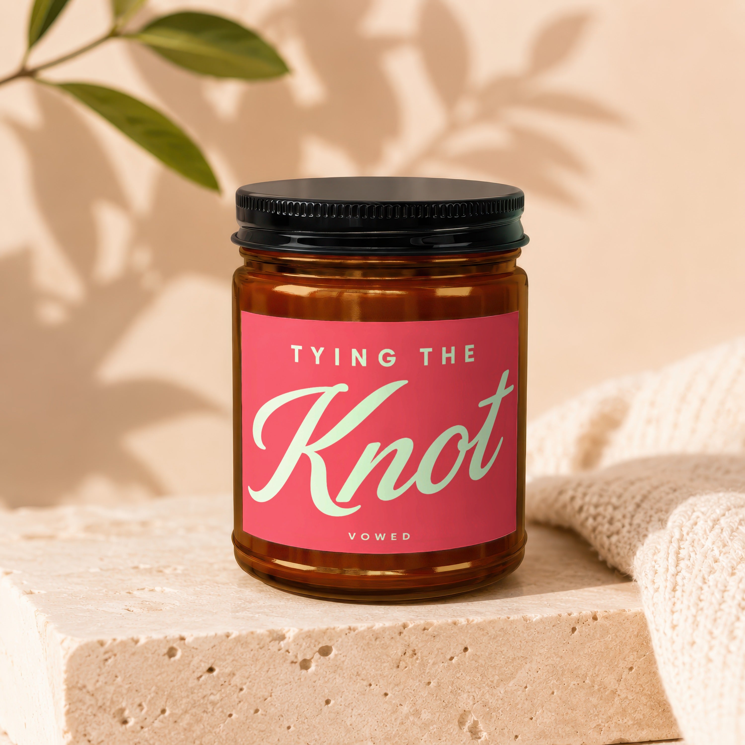 Brown glass candle with pink label reading "TYING THE Knot" and "VOWED".