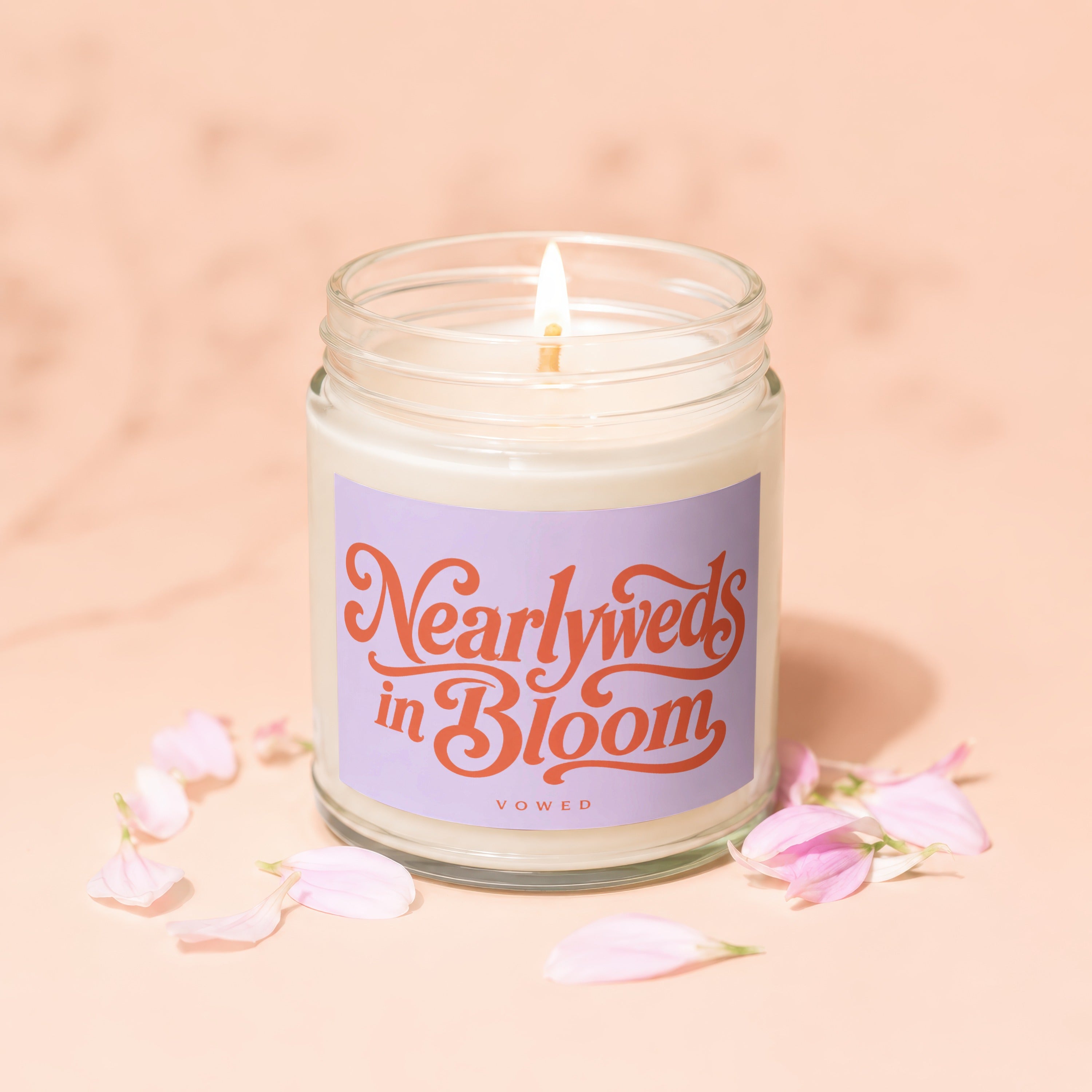 A lit glass jar candle with "Nearlyweds in Bloom" text and "VOWED" below.