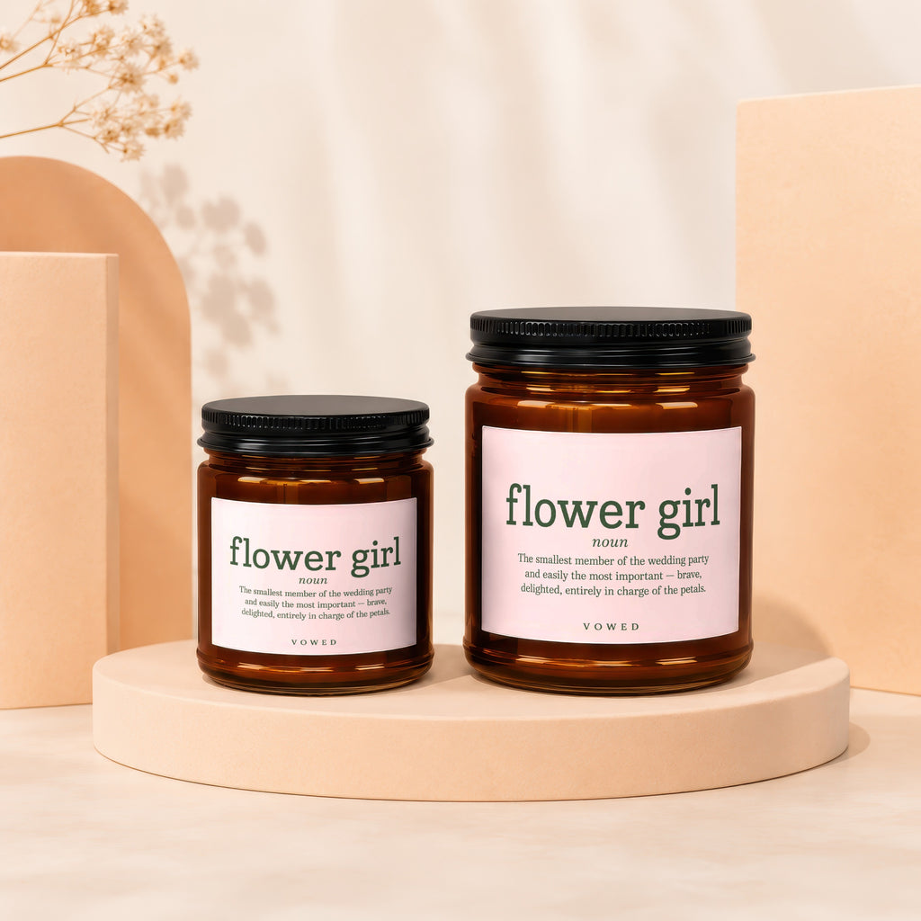Two amber glass candles labeled "flower girl" with pink labels and black lids.