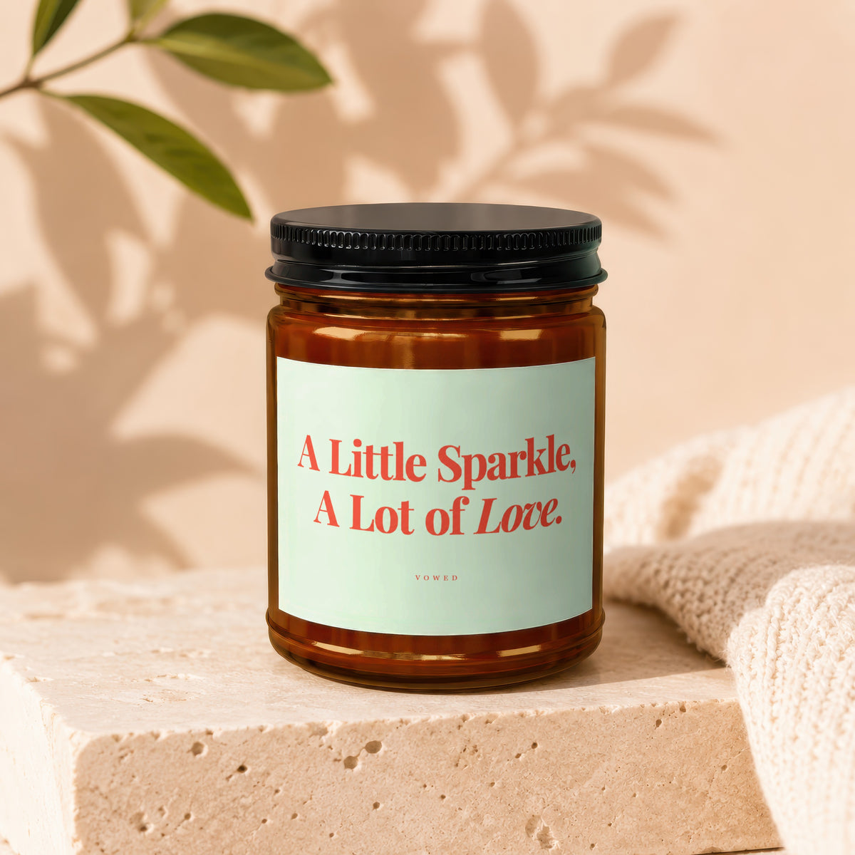 Amber jar candle with light green label reading "A Little Sparkle, A Lot of Love. VOWED".