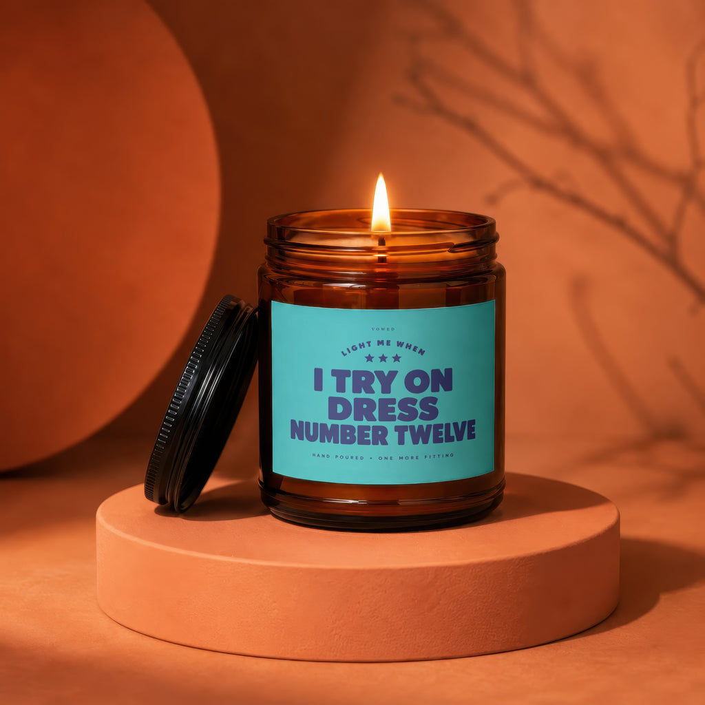 Amber jar candle with teal label reading "I try on dress number twelve".