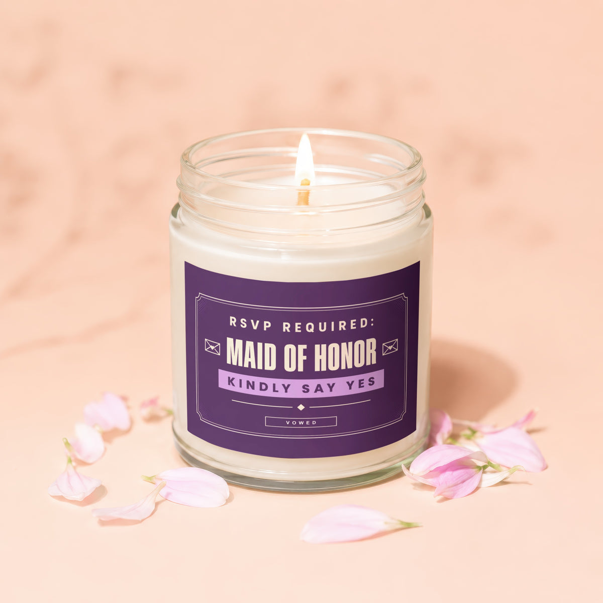 Lit candle in a jar with purple label reading "Maid of Honor Kindly Say Yes".
