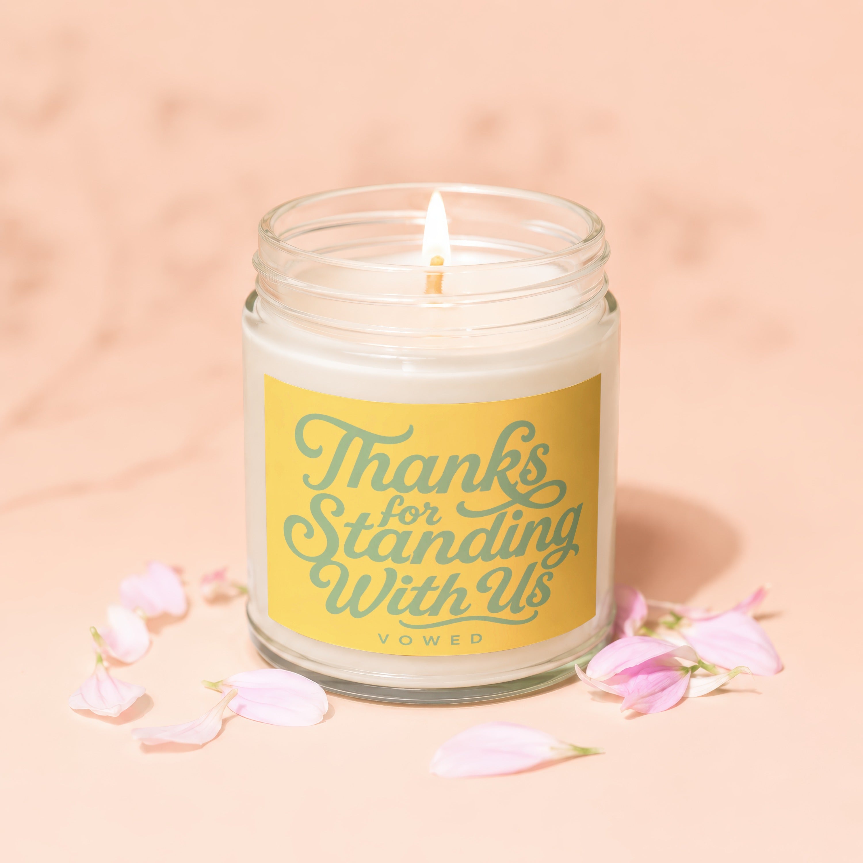 Candle with yellow label reading "Thanks for Standing With Us" surrounded by petals.