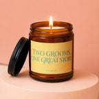 Amber jar candle with lit flame and black lid, captioned "TWO GROOMS, ONE GREAT STORY".