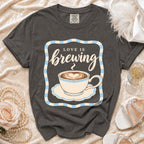 Dark grey t-shirt with "Love is brewing" and coffee cup graphic.