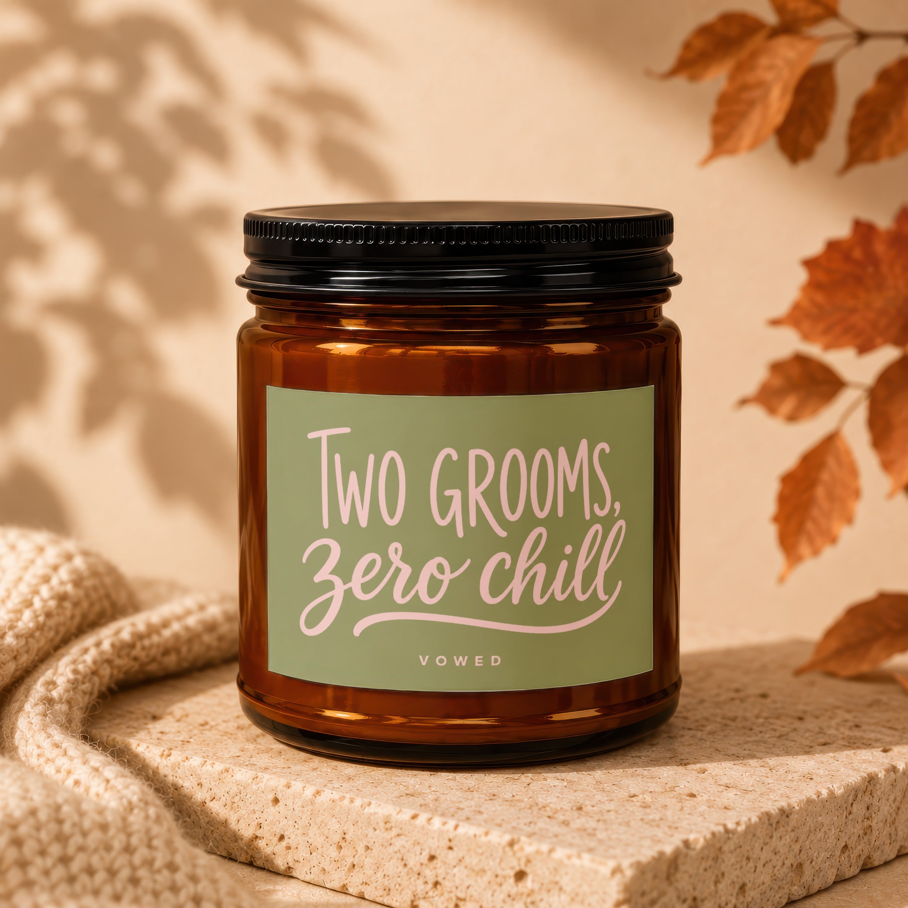Amber jar candle with a green label reading "TWO GROOMS, ZERO CHILL" and "VOWED".