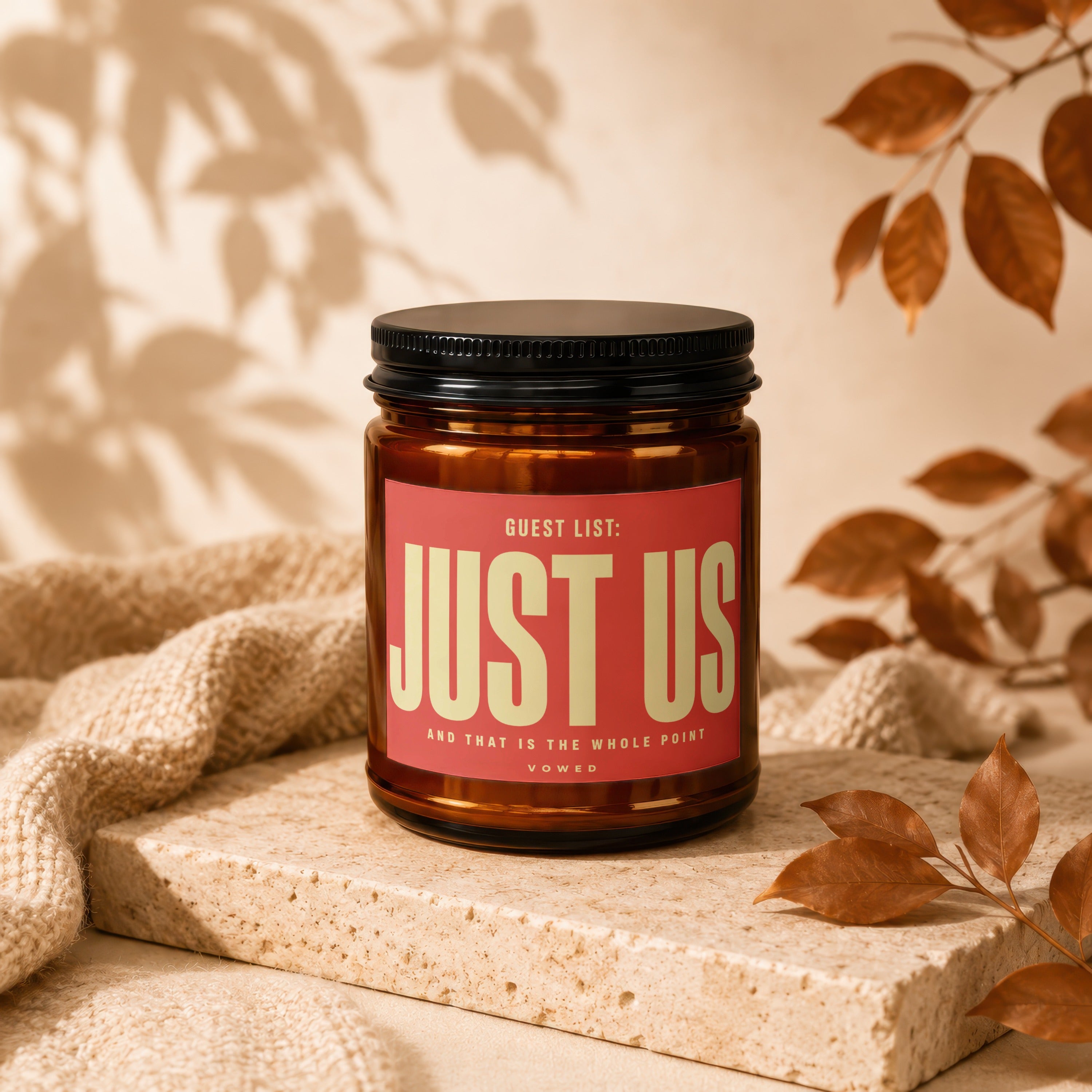 Amber candle with black lid and red label reading "JUST US"